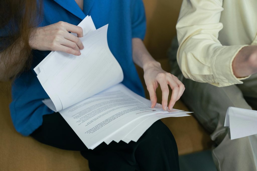 People in professional attire reviewing important documents together on a sofa.